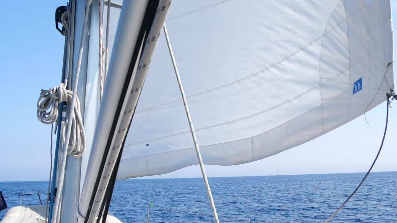 在公海上航行的帆船。风吹着游艇的白帆，阳光灿烂。概念:航海假期，自由视频素材