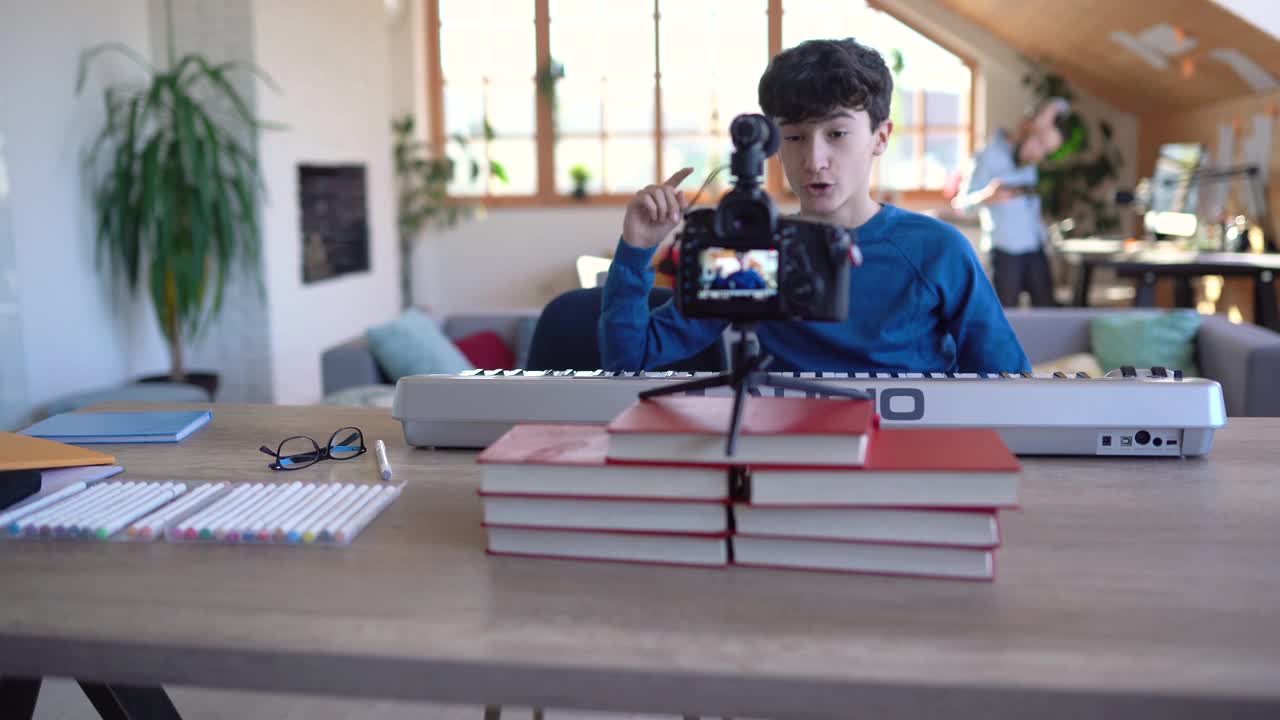 十几岁的男孩录制视频教程关于在家里玩合成器视频素材