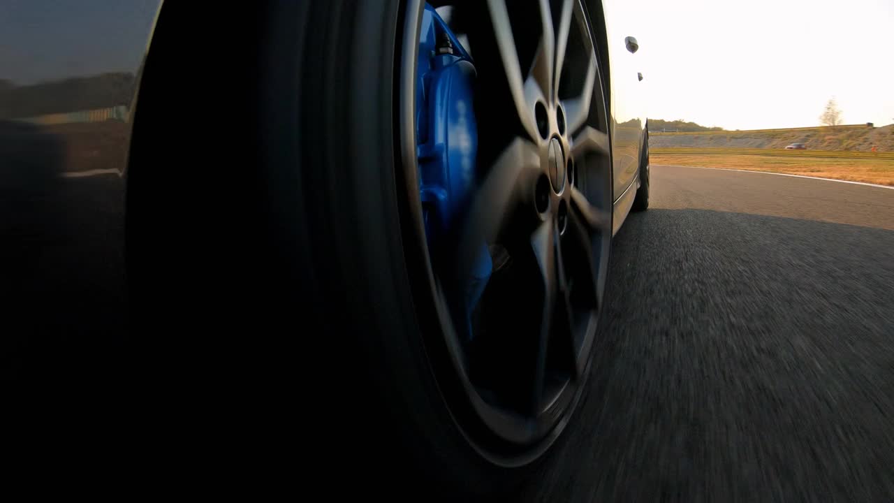 特写镜头的运动赛车车轮旋转，驾驶在赛车轨道在日落视频素材