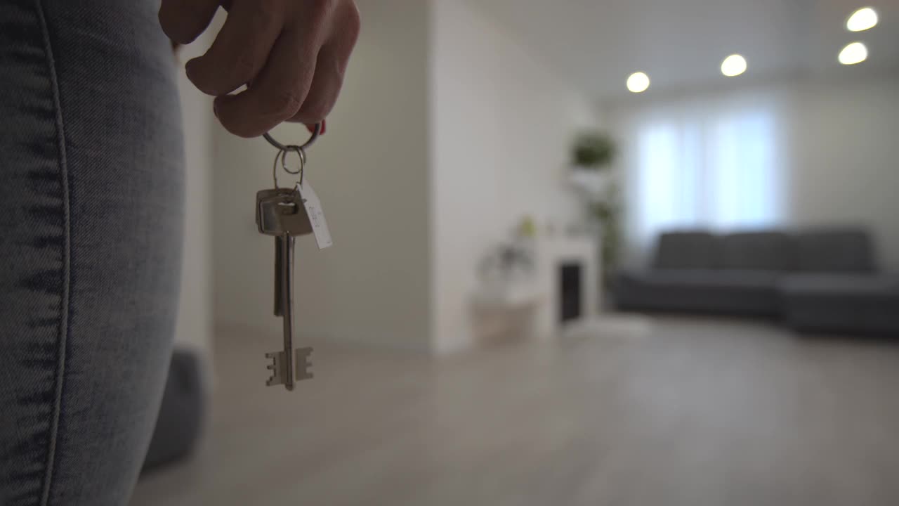搬进新公寓，女人拿着钥匙走进她的新公寓，空荡荡的白色房间，新房建设。视频素材