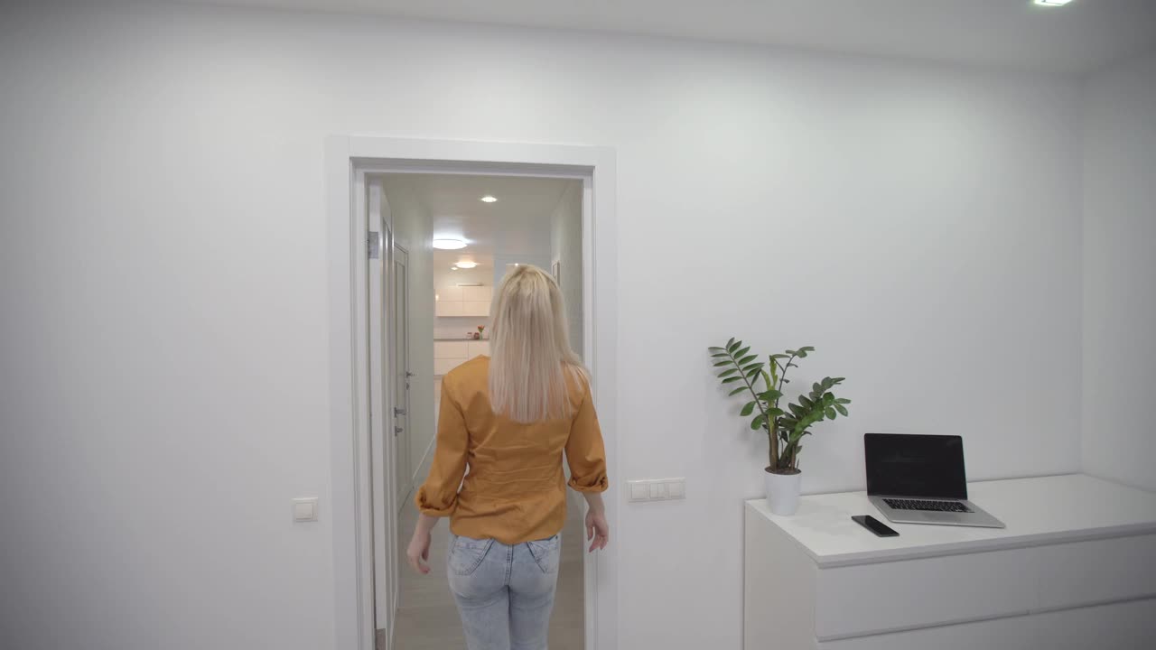 搬进新公寓，女人拿着钥匙走进她的新公寓，空荡荡的白色房间，新房建设。视频素材