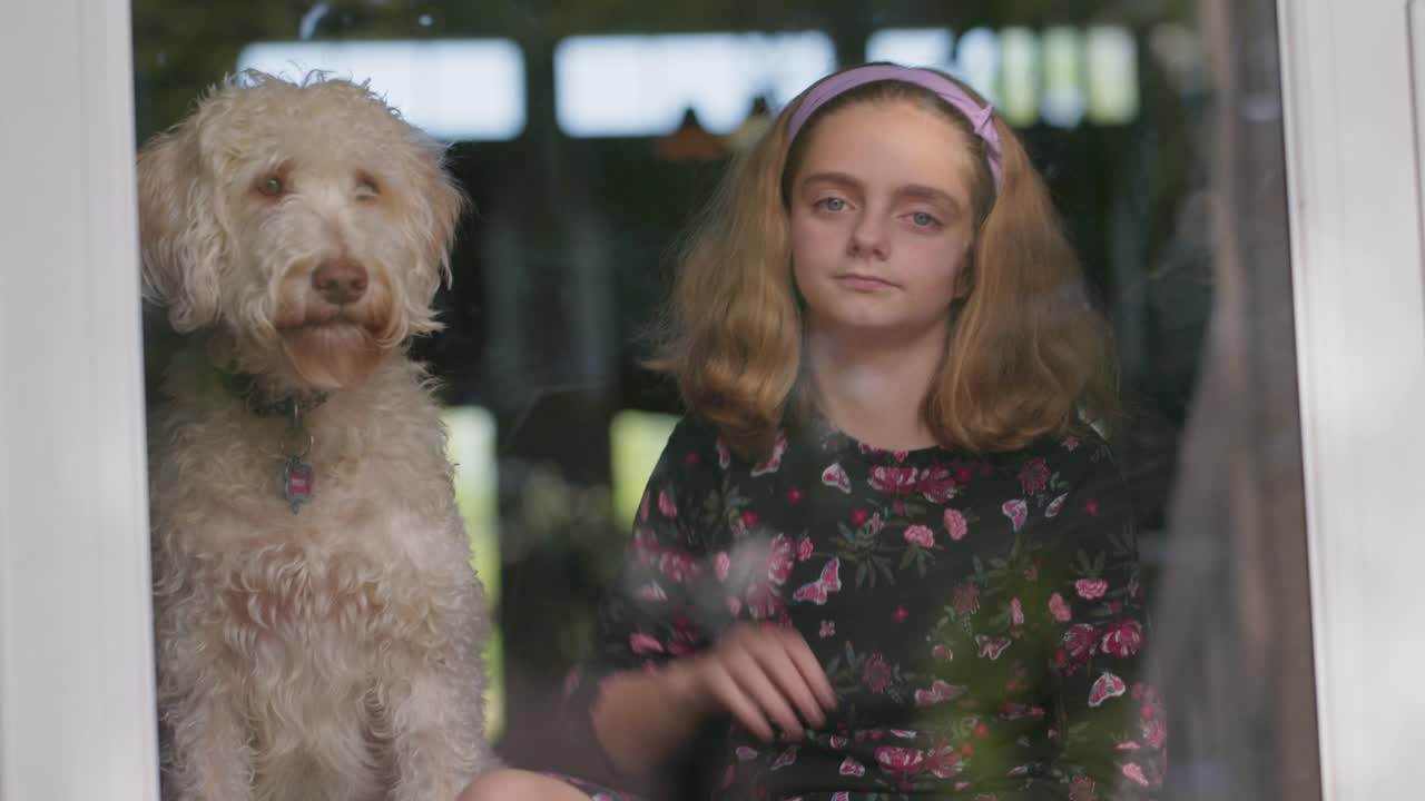 小女孩把头靠在她的狗身上看镜头视频素材