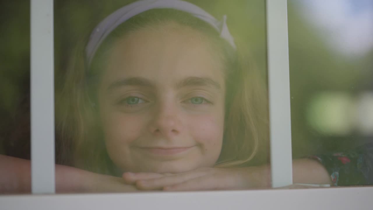 CU肖像的年轻女孩微笑着看着窗外的相机视频素材