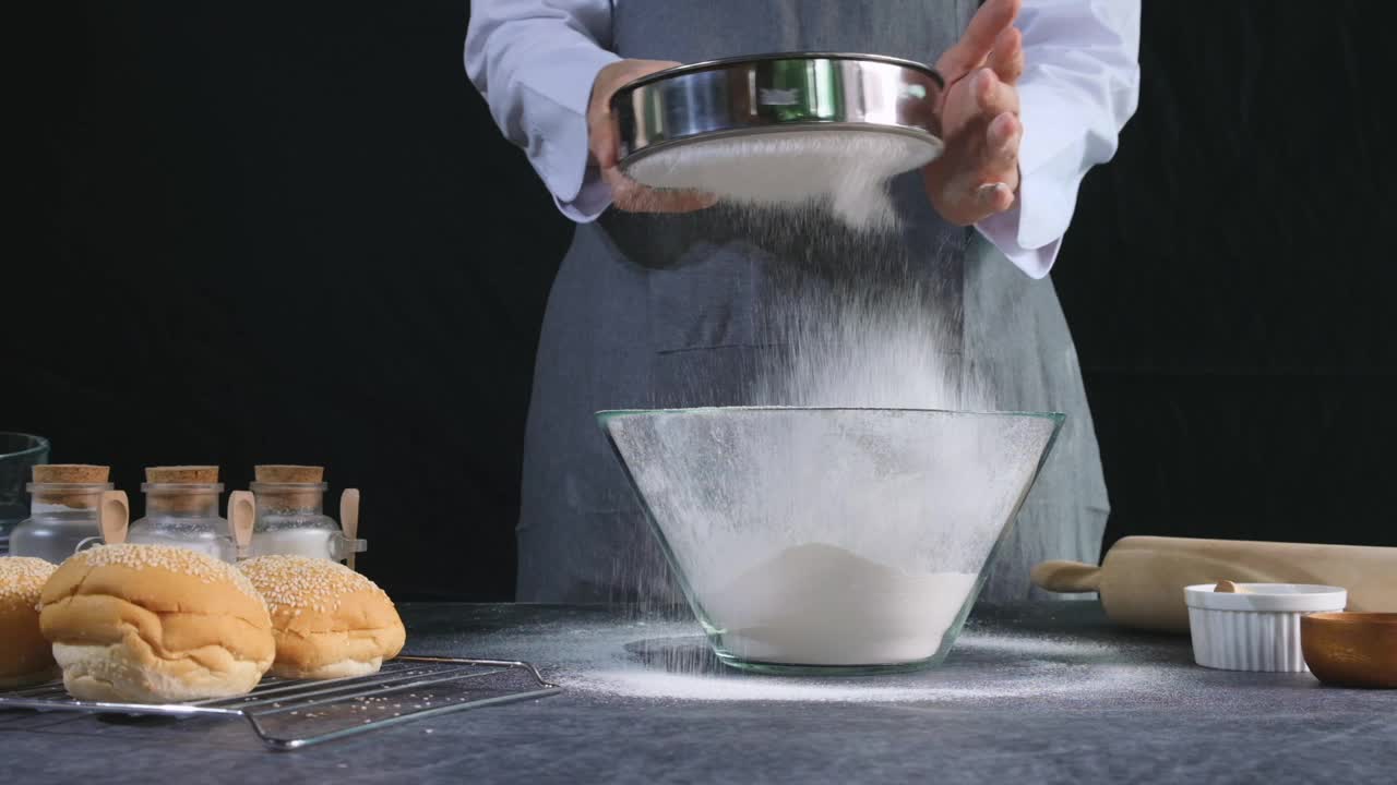 面包师将面粉用筛子筛入碗中。自制烘焙概念，慢动作拍摄。视频素材