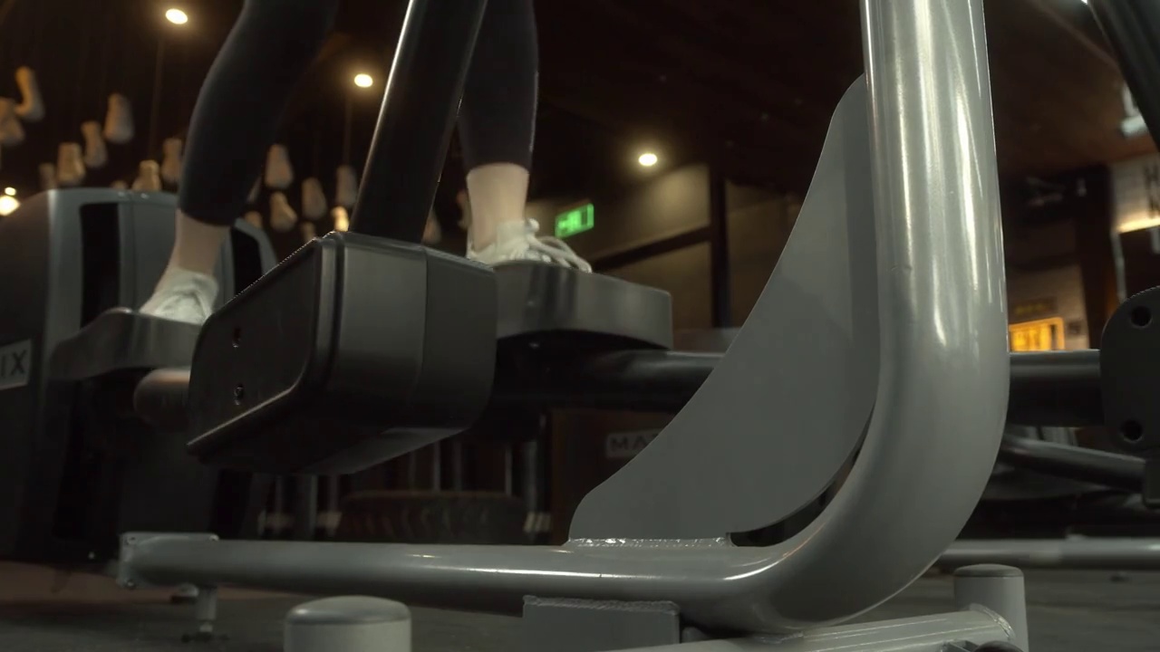 迷人的年轻女性健身在椭圆机健身在健身房视频素材