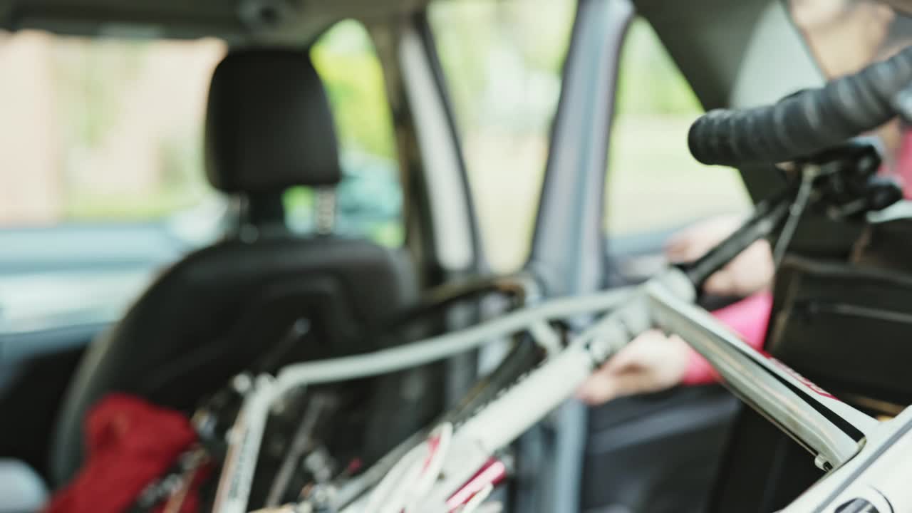 50岁出头的女性自行车手在汽车后面保护自行车视频素材