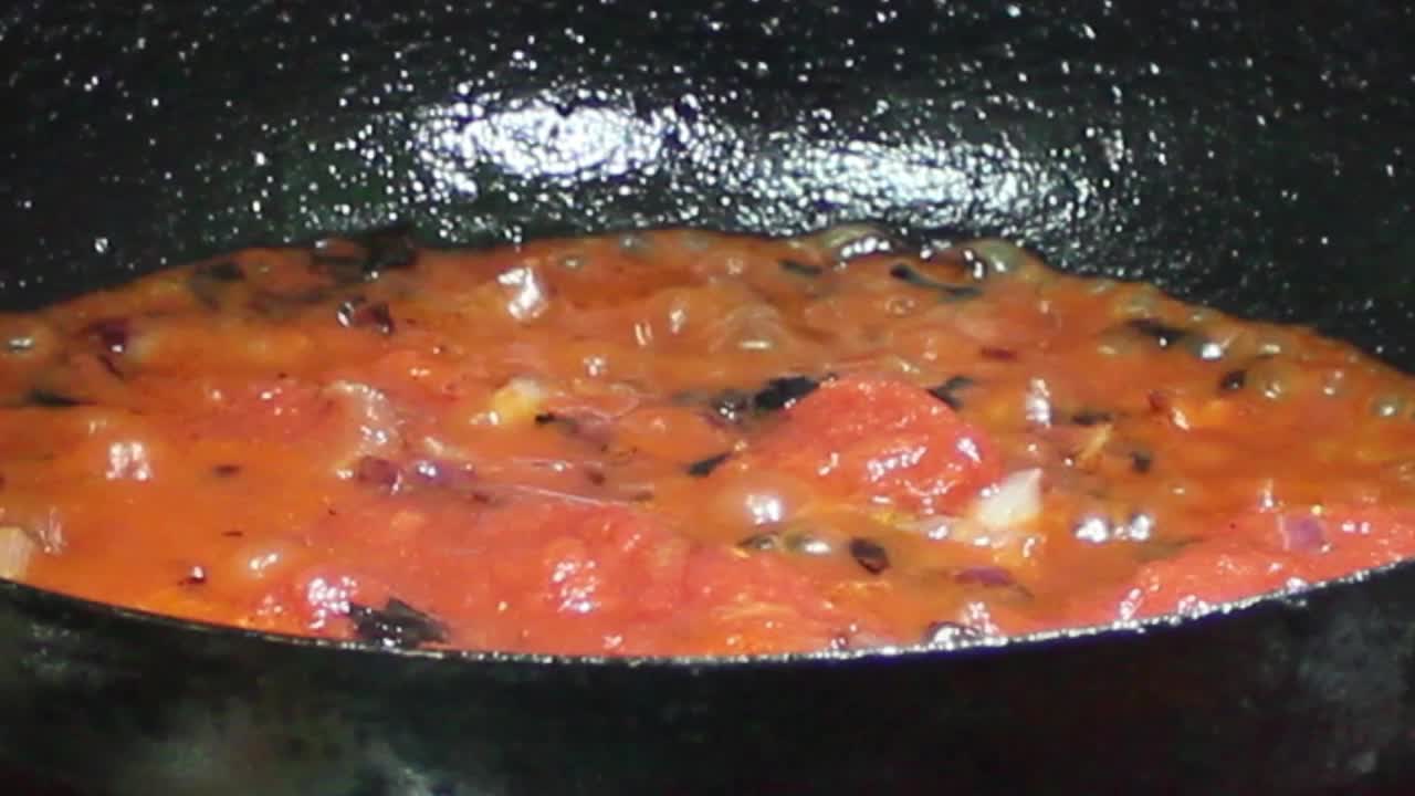 用特写镜头在煎锅里煎西红柿和洋葱。视频下载
