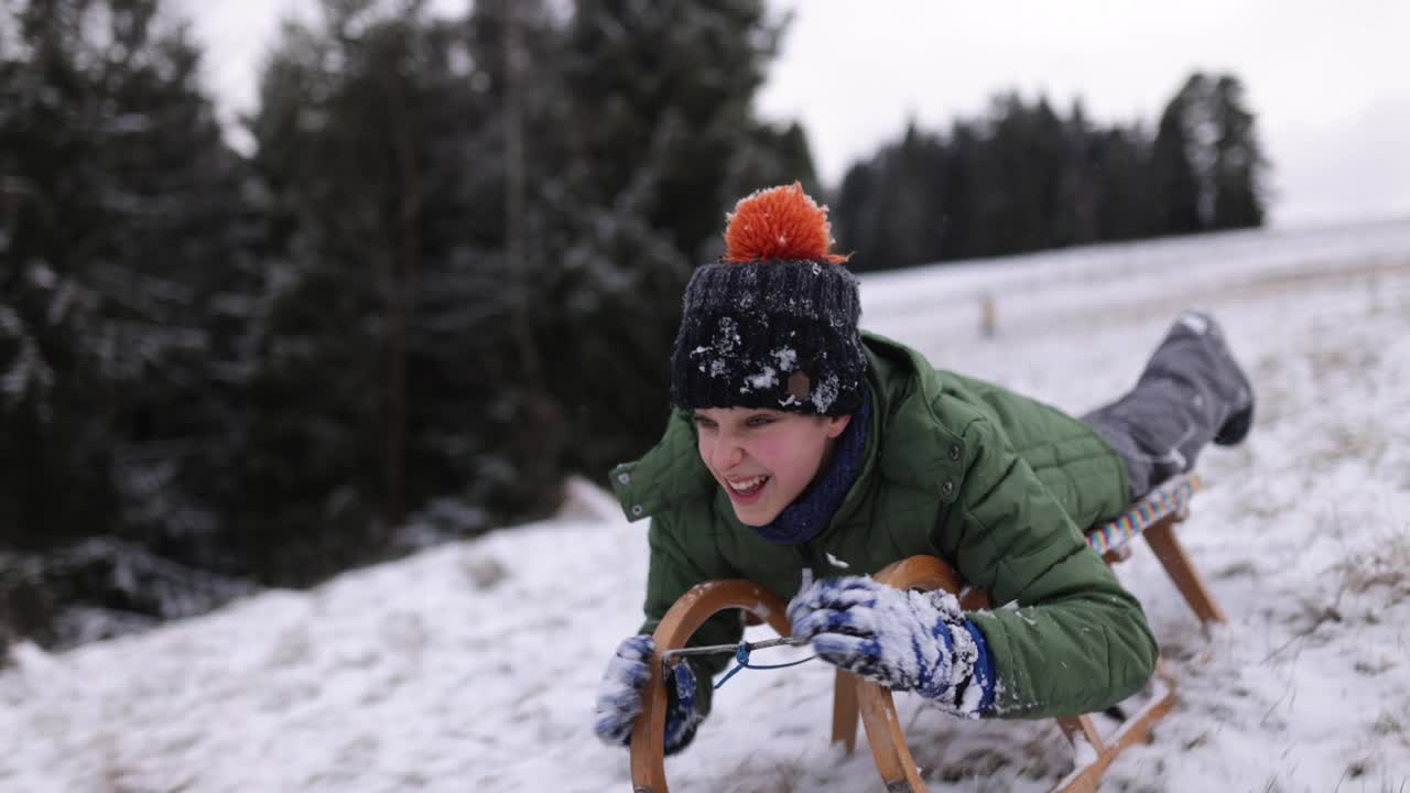 冬天的一天，小男孩在山上拉雪橇视频下载