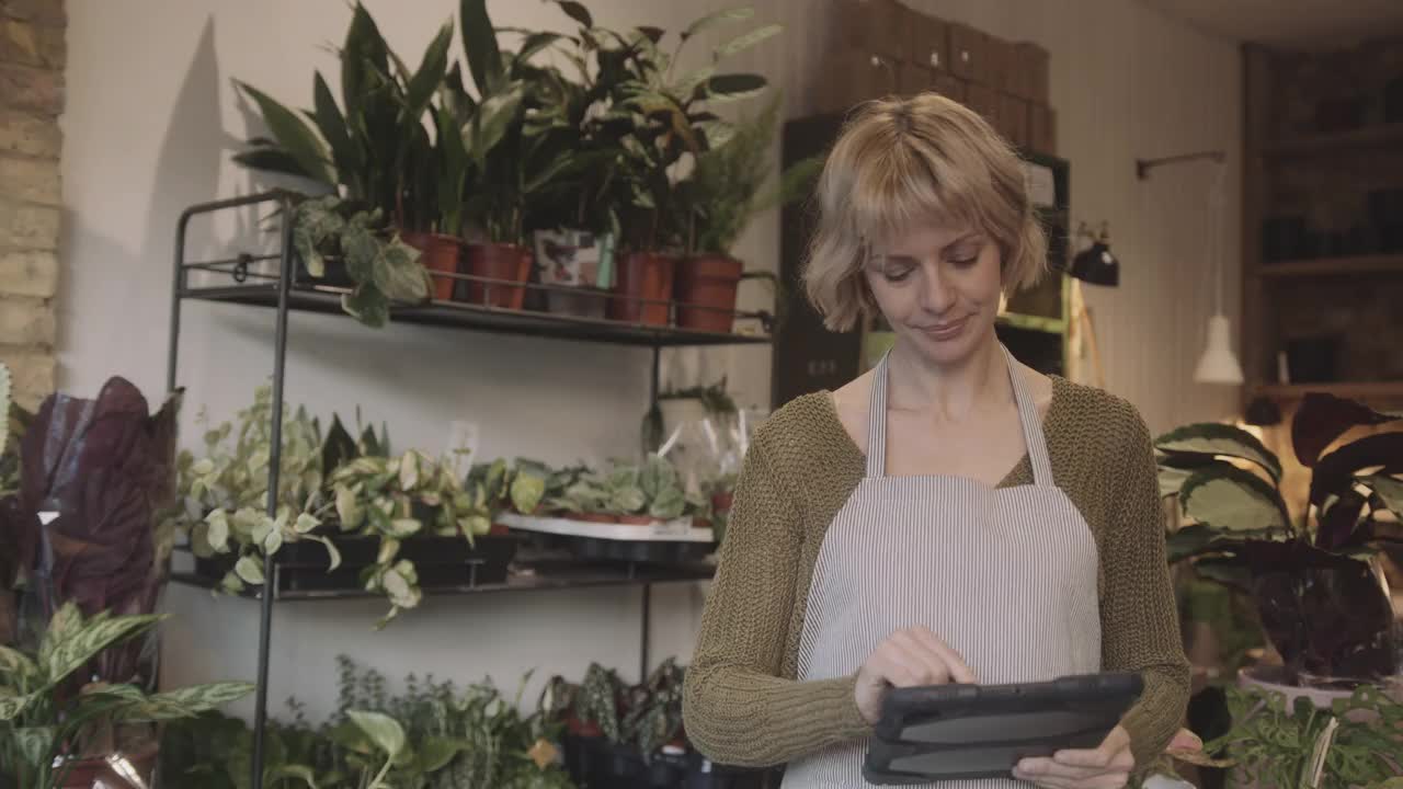 成熟的女性小企业主穿着围裙在商店里用平板电脑清点存货视频素材
