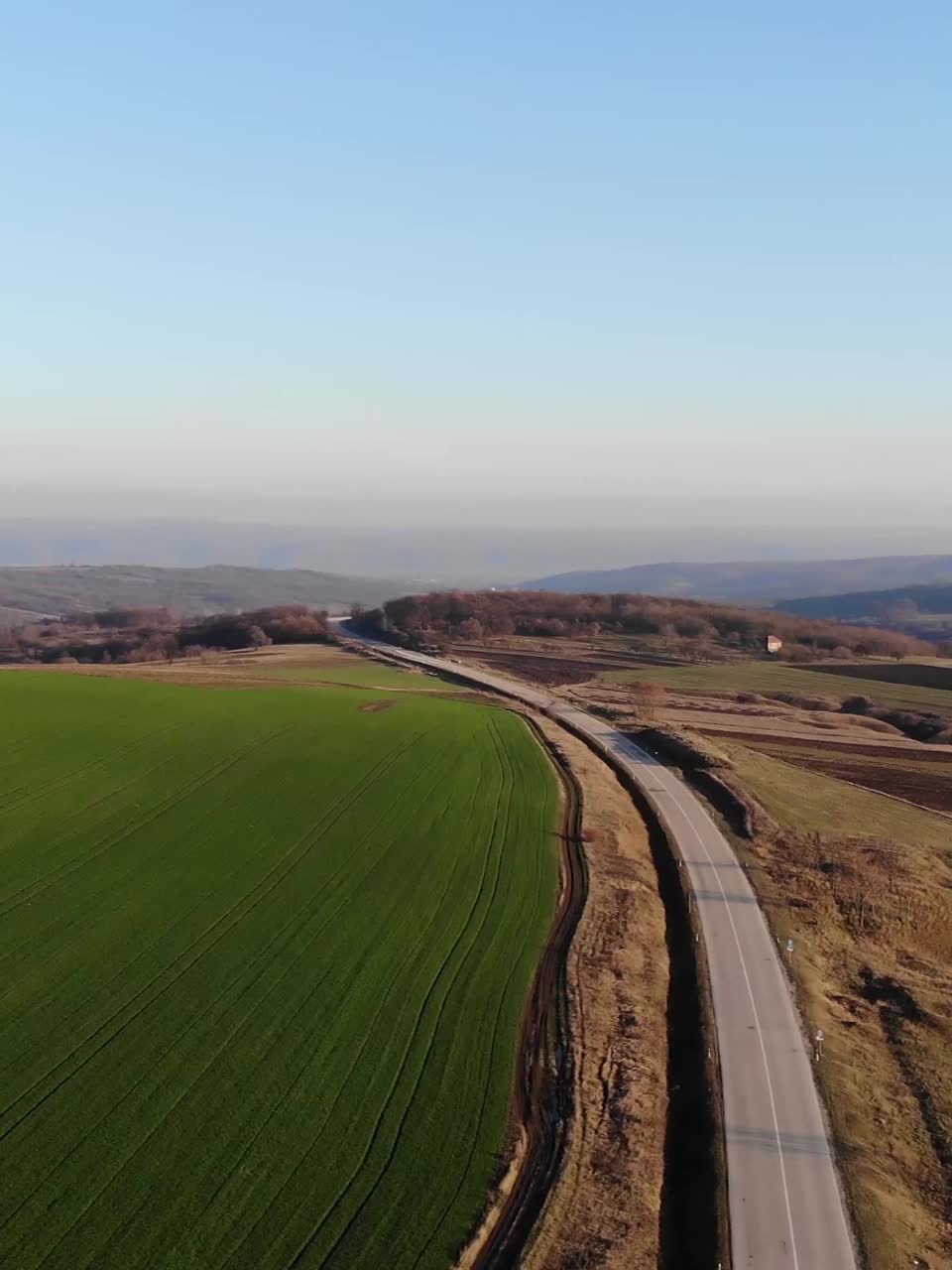 由无人机拍摄的垂直4k视频。汽车驶入金色的夕阳中。俯视图美丽的自然和救济-东欧-塞尔维亚视频素材