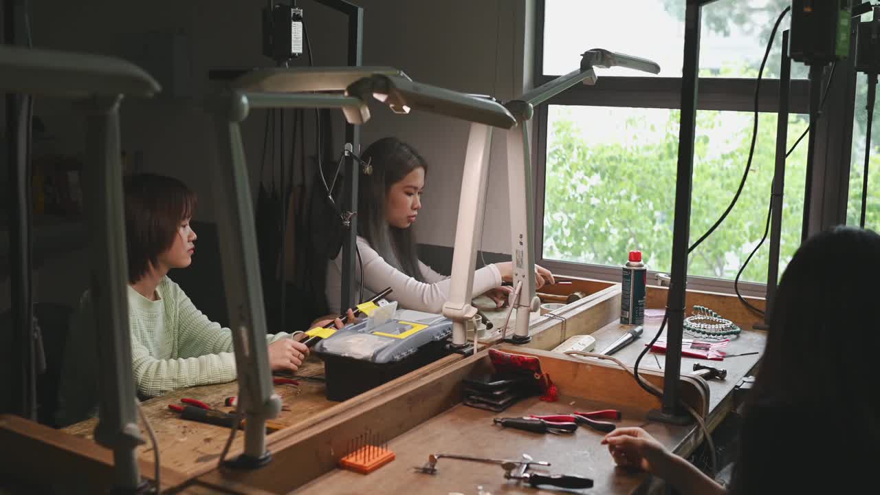 亚裔华裔女大学生在工作台上并排制作珠宝设计视频素材