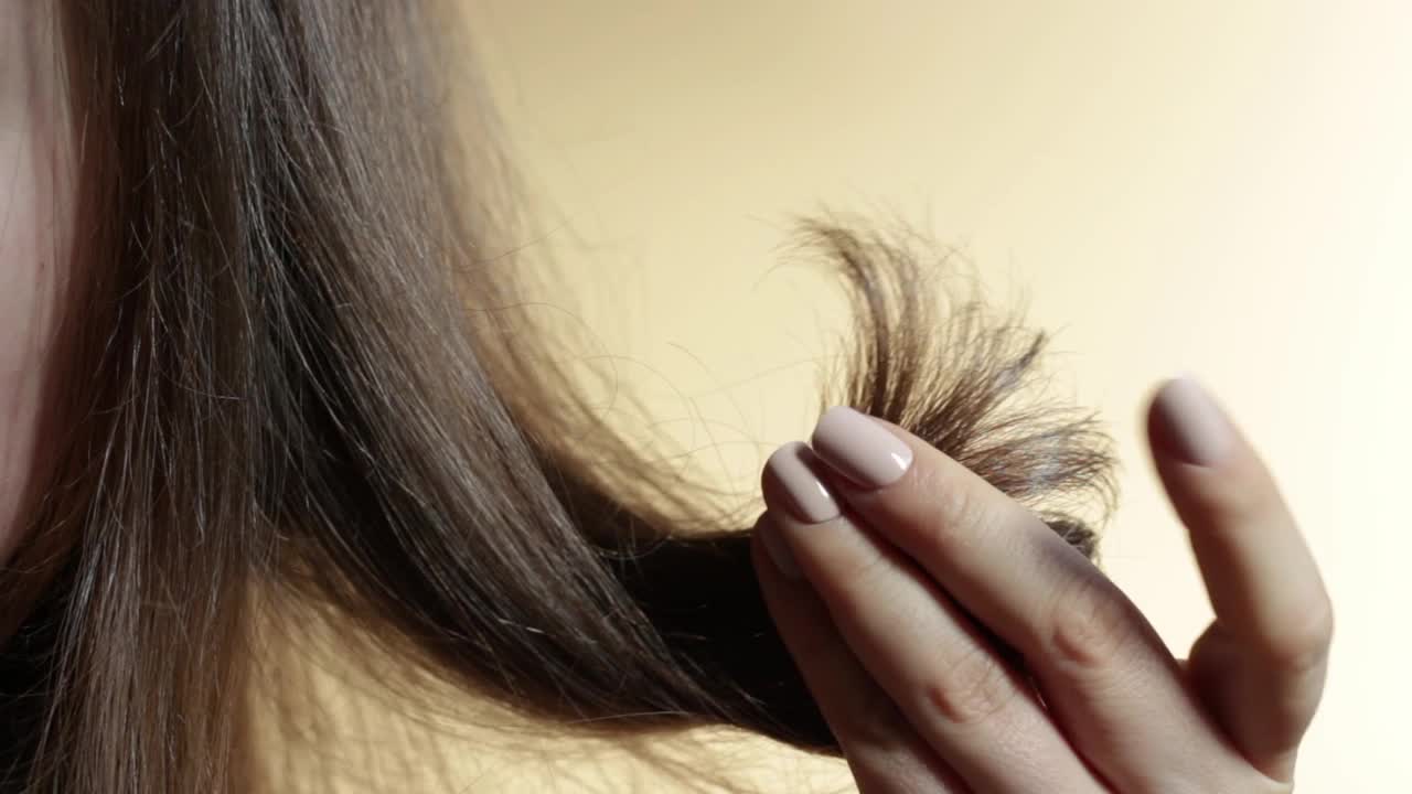 女孩握着她的头发分叉在她的手近距离。视频素材