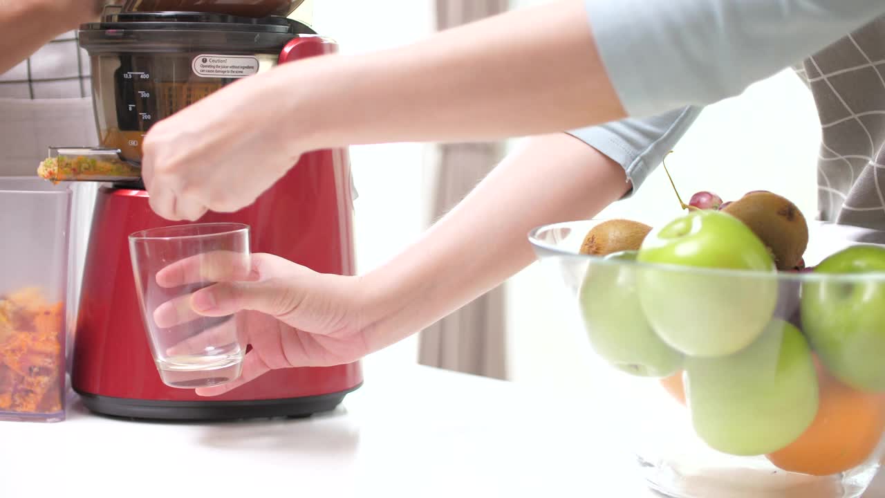 冷榨果汁与苹果、橙、胡萝卜混合在冷榨机中视频下载
