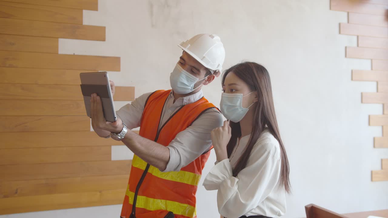 白人男性建筑师讨论和展示建筑图纸上的数字平板给亚洲女性客户。视频素材