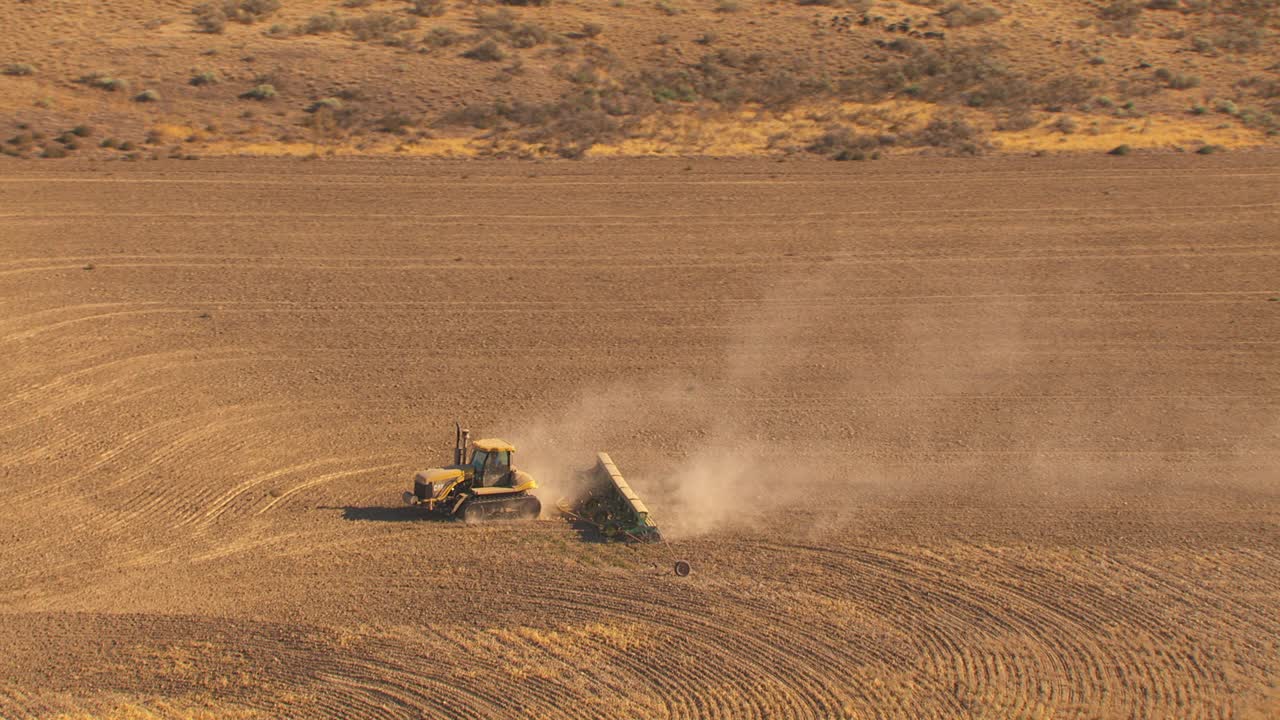 一种大型拖拉机，为准备种植而在大片土地上耕作褐色土壤。视频素材