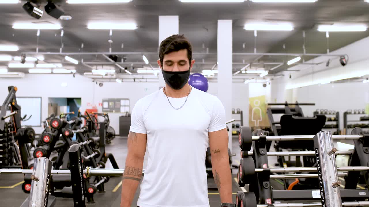 肌肉发达的拉丁男子在健身房戴着防护面具使用哑铃视频素材