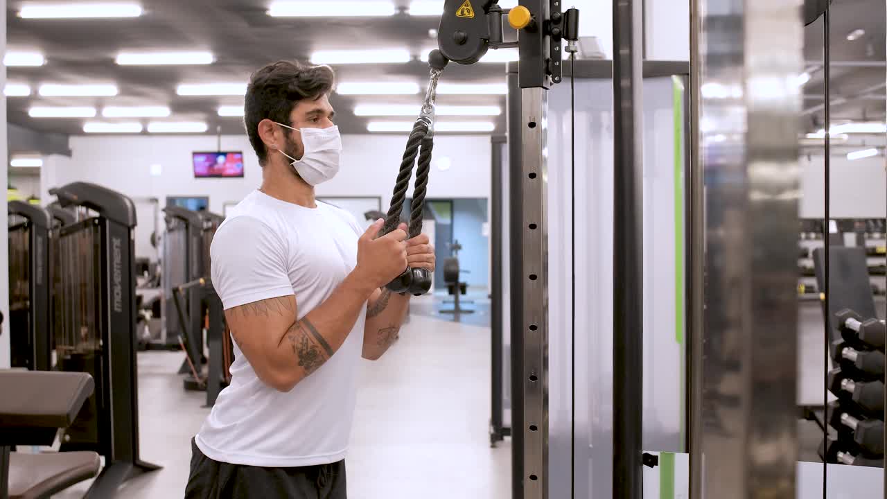 肌肉发达的男子戴着防护面罩在健身器材上训练视频素材