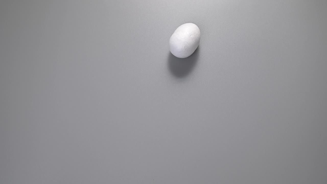 复活节。许多鸡蛋滚着同样的颜色，白色的，滚着灰色的背景。俯视图，停止运动。极简主义风格。复活节的概念视频下载