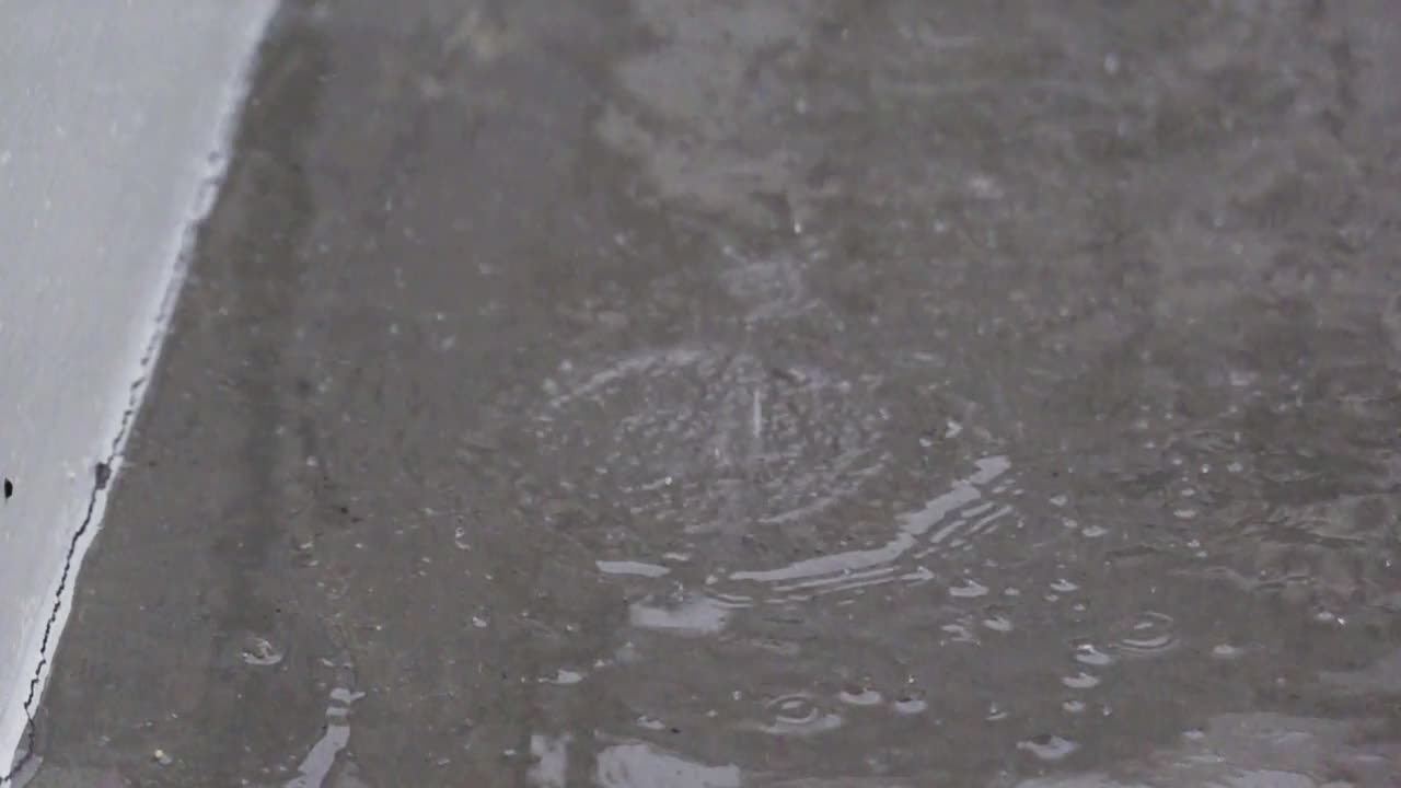 雨点缓慢地落在人行道上。视频素材