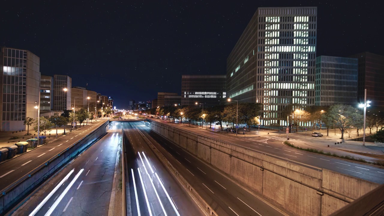 夜晚时光流逝的城市高速公路与快速移动的汽车旅行的现代商业区。在一个繁星满天的美丽夜晚，城市交通的轻轨视频下载