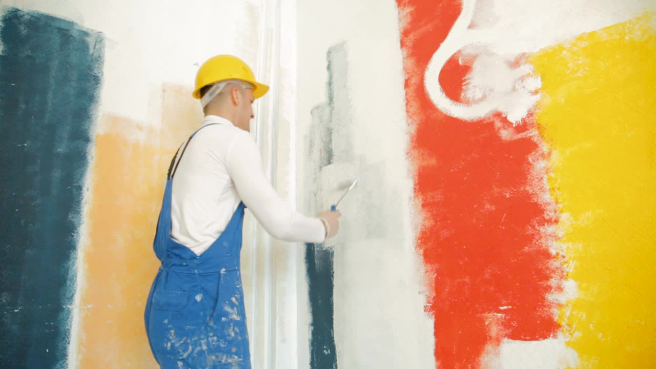 穿着白色高领毛衣的专业画家正在用滚轴刷墙，并竖起大拇指视频下载