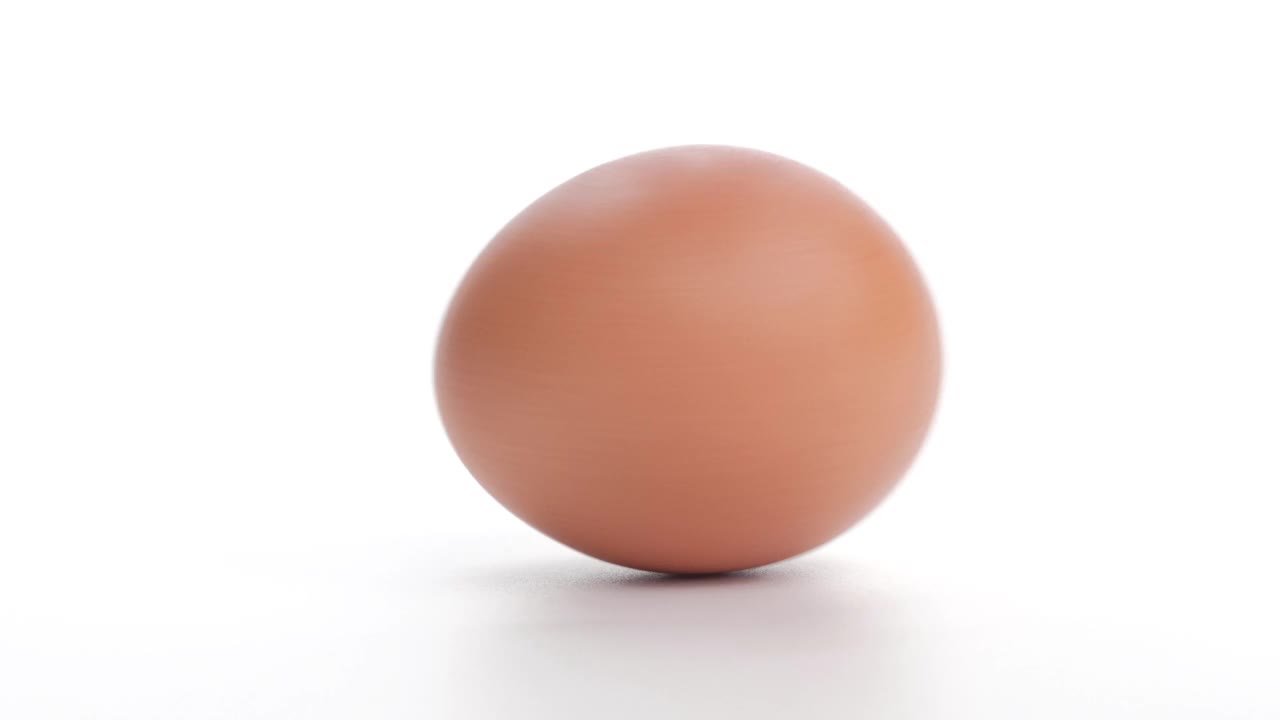 鸡蛋被孤立滚动在白色的背景上，复活节彩蛋的背景。视频下载