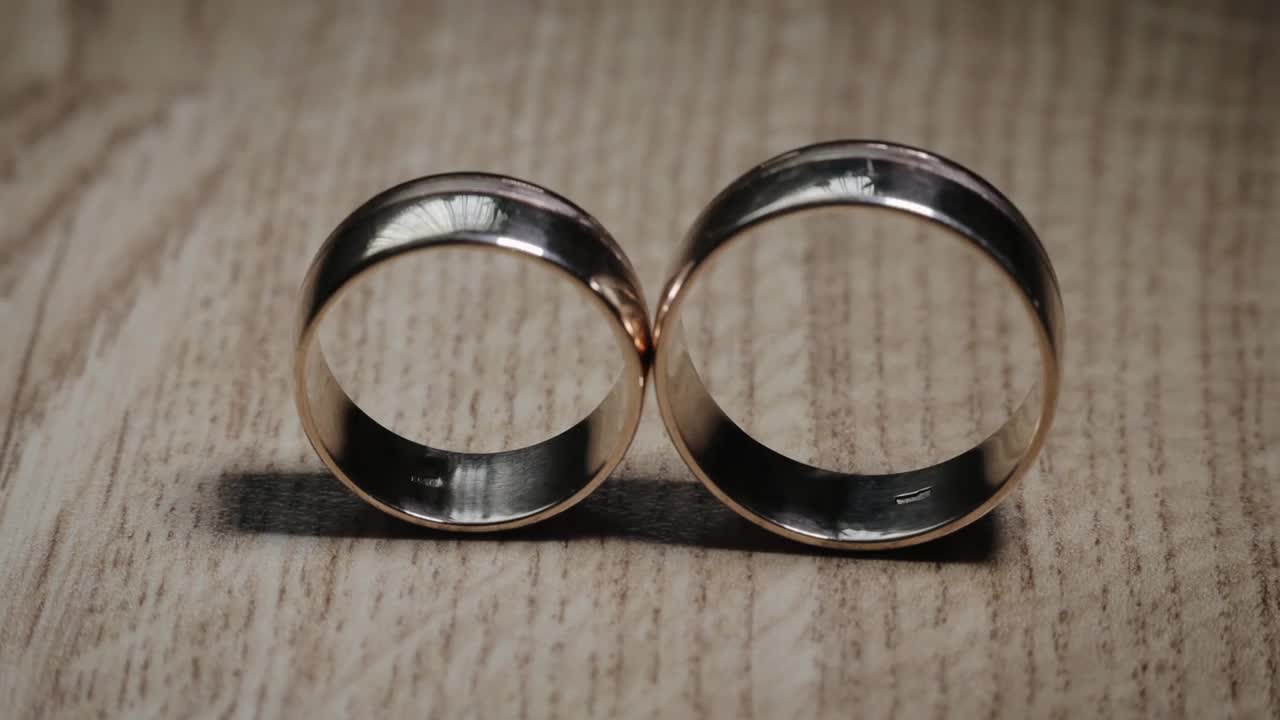 两个金婚戒闪亮的近距离微距。把光注入结婚金戒指上。慢动作视频下载