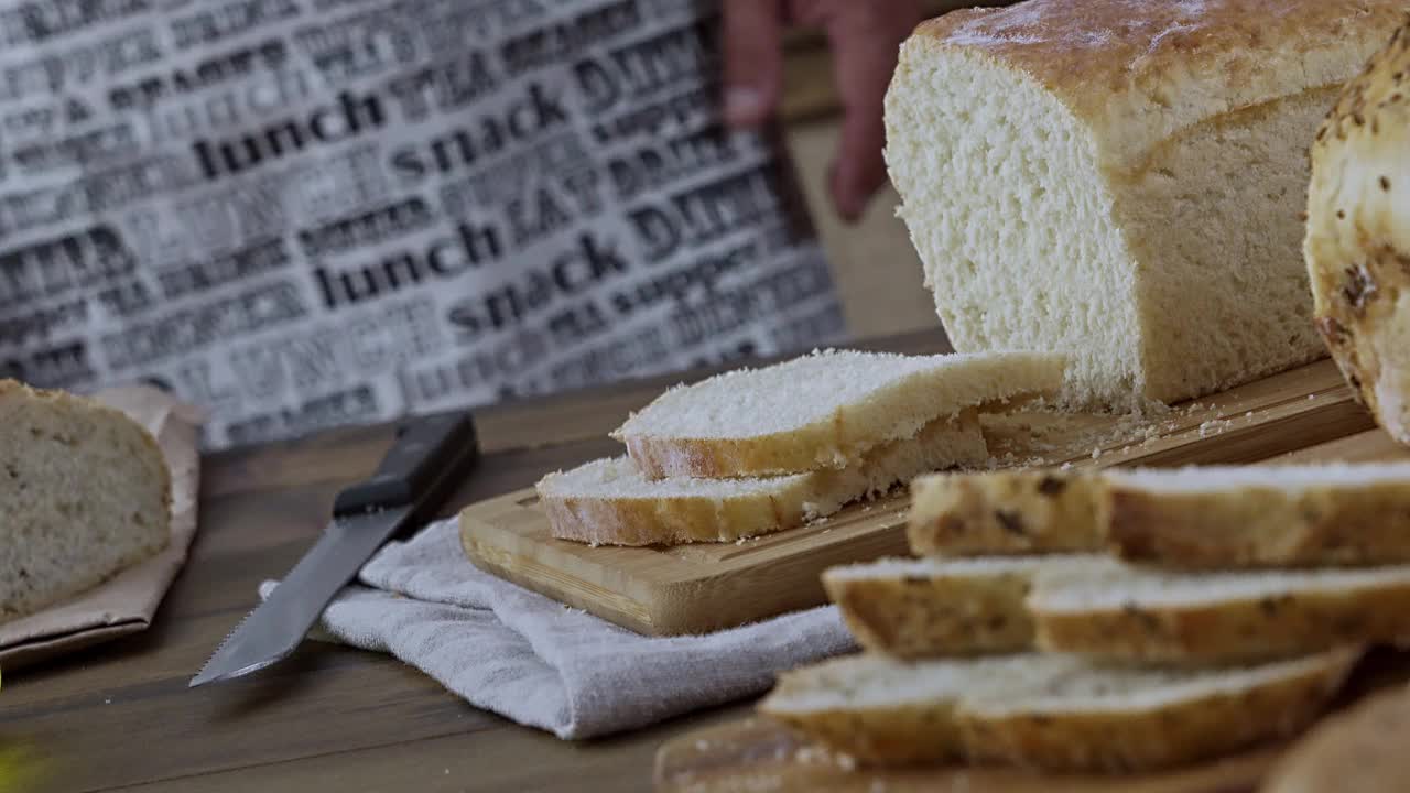 男子在木板上切面包的特写镜头。酵母面包切片视频素材