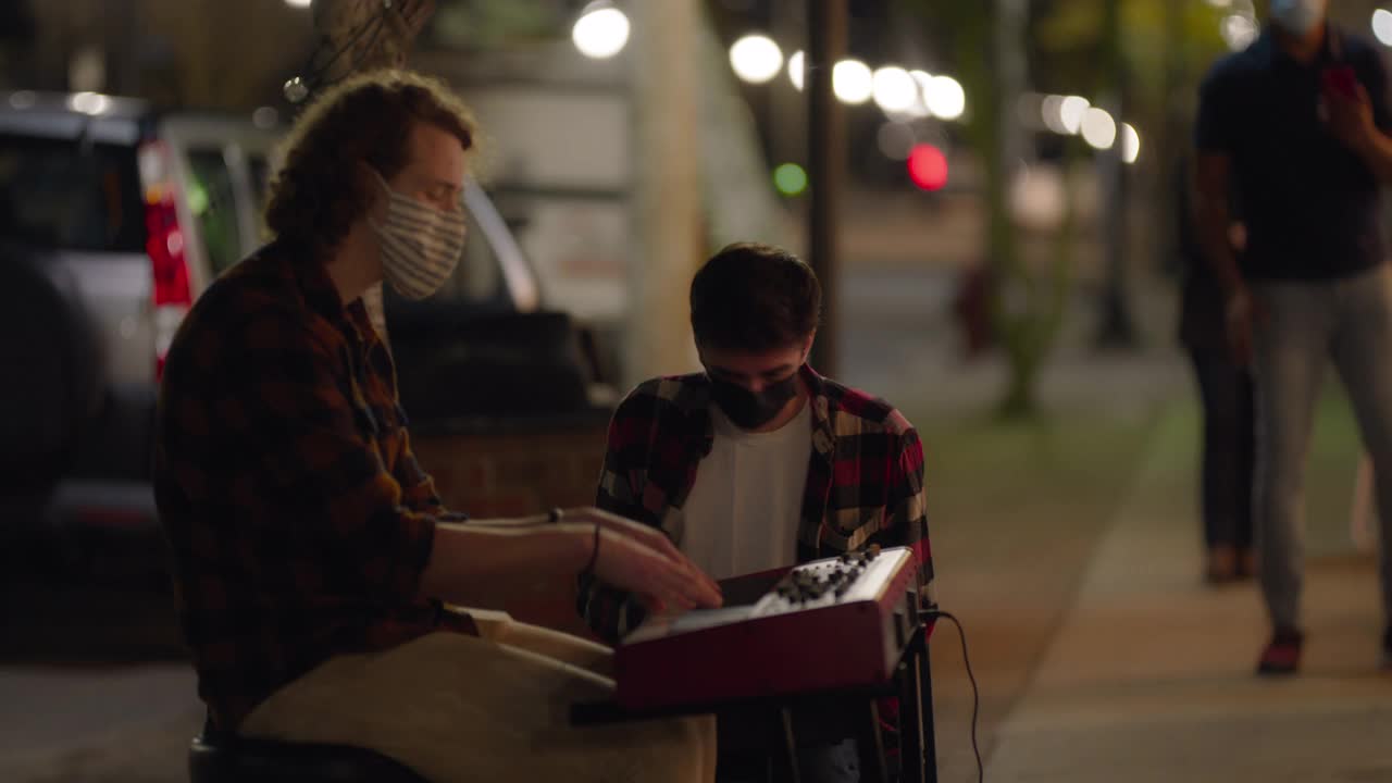 人们戴着面具一边取餐，一边欣赏街头艺人的表演视频下载