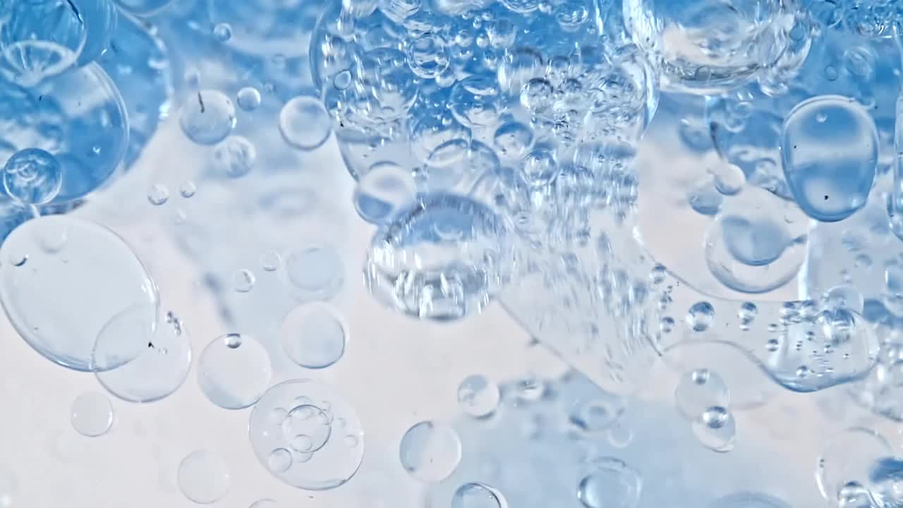微距拍攝的各種氣泡在水上升在輕白色背景。液體霜凝膠透明化妝品樣品紋理與氣泡。潔凈和純潔的概念視頻素材