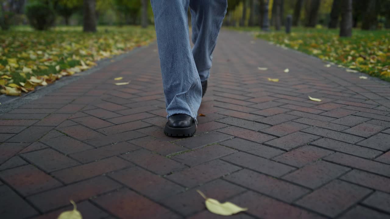 近距离观察在秋天公园里穿着靴子和牛仔裤的不明女性。放松的时间视频下载