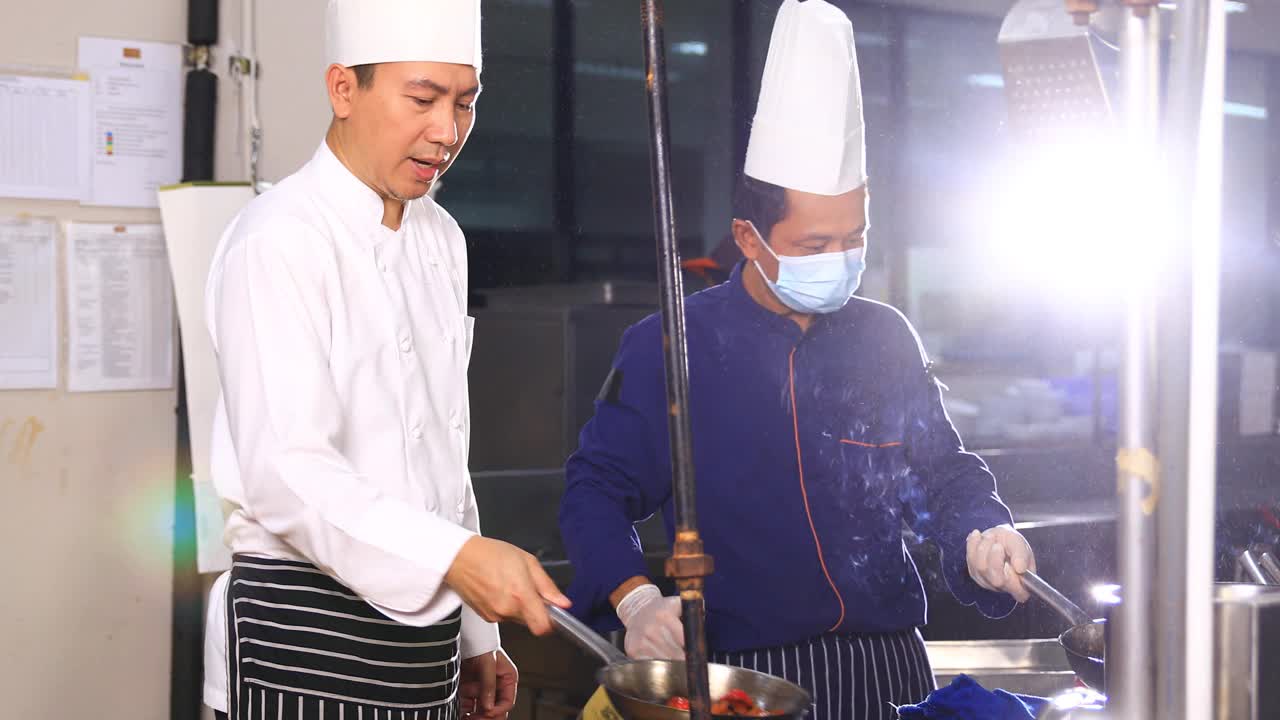 一位亚洲男性和他的团队厨师在酒店餐厅的专业厨房里做饭视频素材