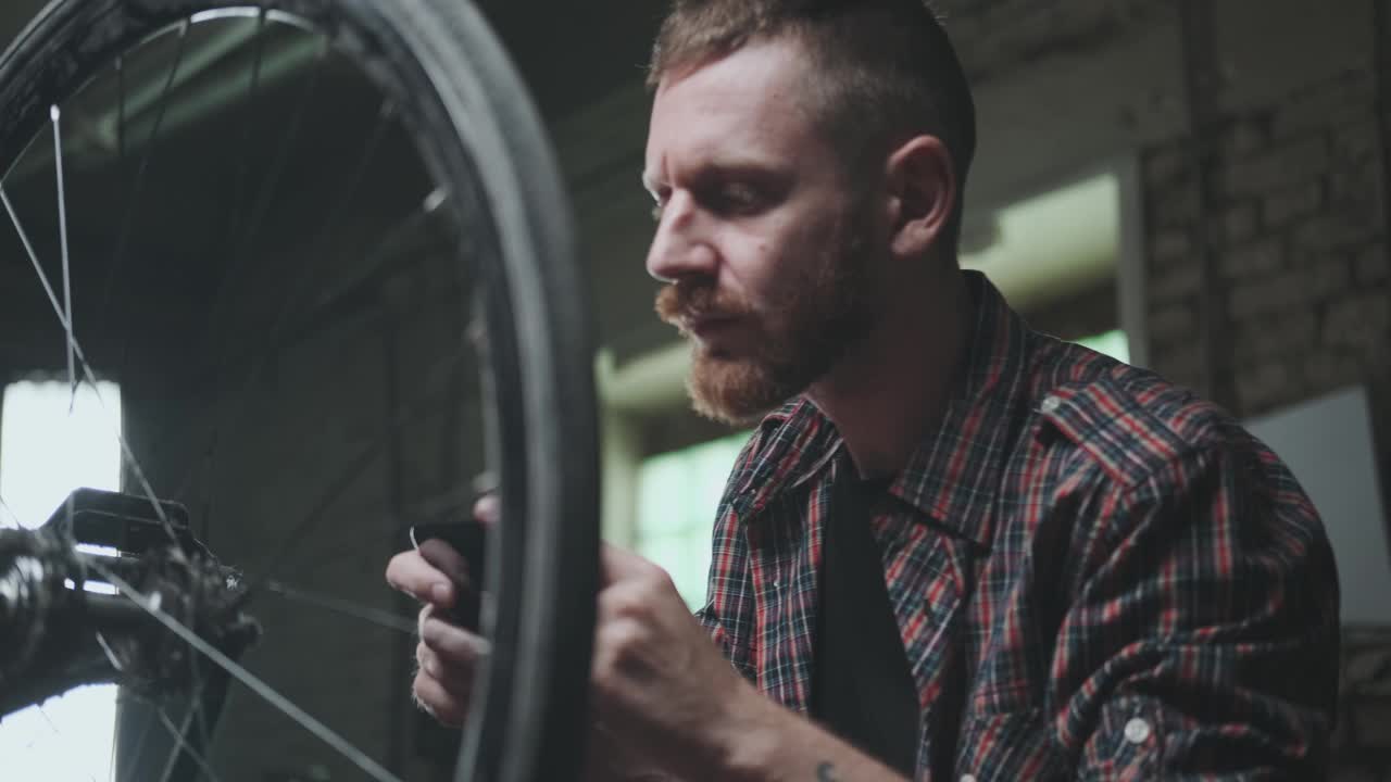 一个年轻的骑自行车的男性拍下了一个汽车轮子的照片，以出售或寻找一个备件修理。视频下载
