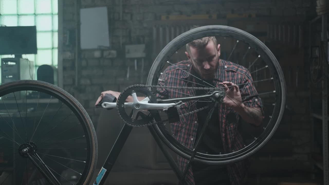 大气车间，修理厂:一个留着胡子的潮人正在修理倒立的自行车。视频下载