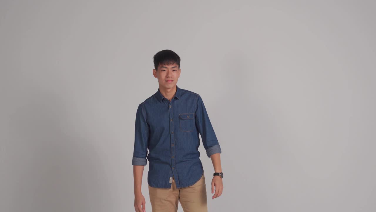 亚洲华人英俊男子微笑着与灰色的背景拍摄工作室视频素材