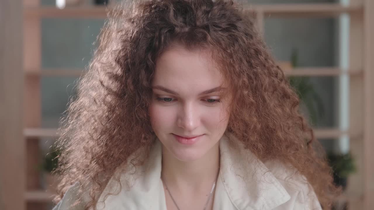 一个年轻的卷发女人的肖像直视着照相机视频下载