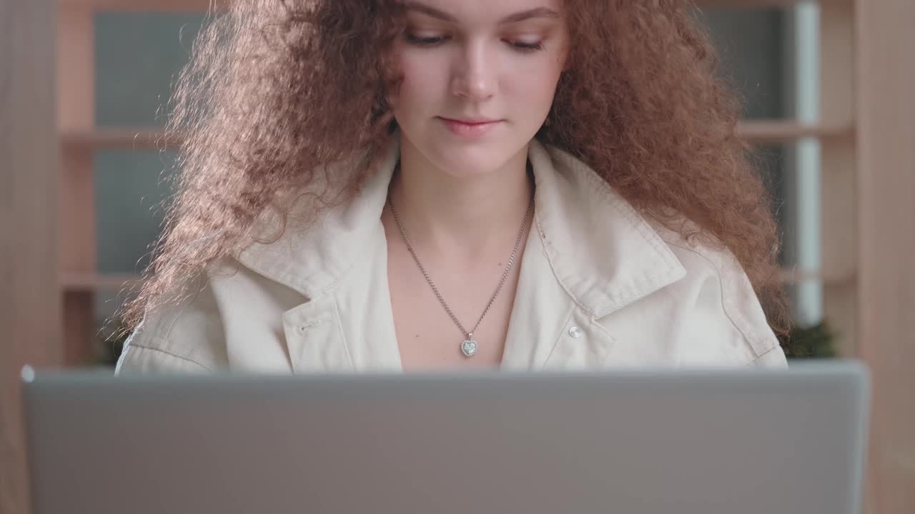 年轻女孩在网上交流，在笔记本电脑上打字，面带微笑视频下载