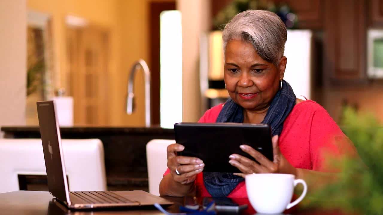 成年女性在家里使用数码平板电脑和笔记本电脑。视频下载
