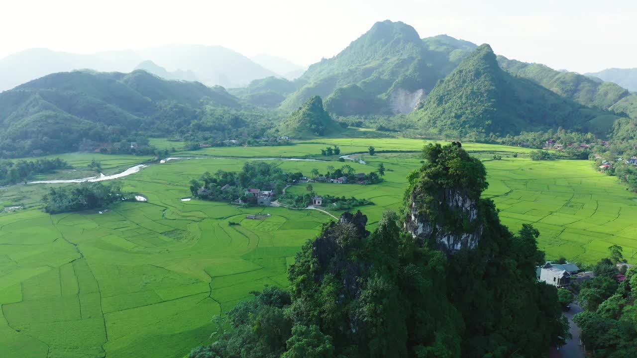 空中拍摄的岩石上的植物对天空，无人机上升在绿色的乡村景观在晴朗的一天-木仓寨，越南视频素材