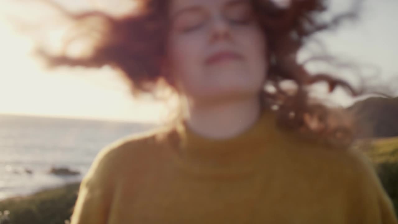 日落时分，一头红卷发的女人在风中摇曳视频下载