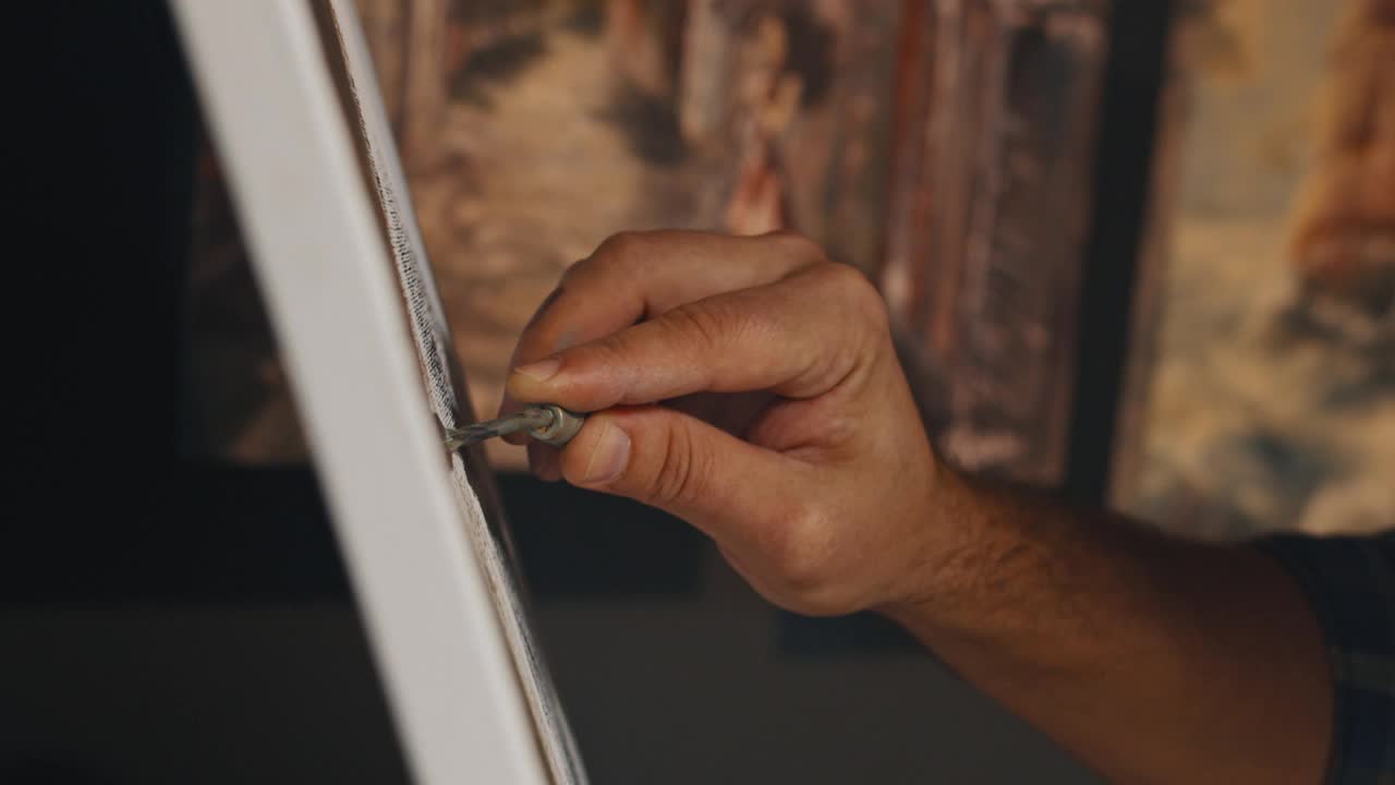 艺术家用小金属抹刀在画布上涂抹油彩，在光线下极近距离地作画视频下载