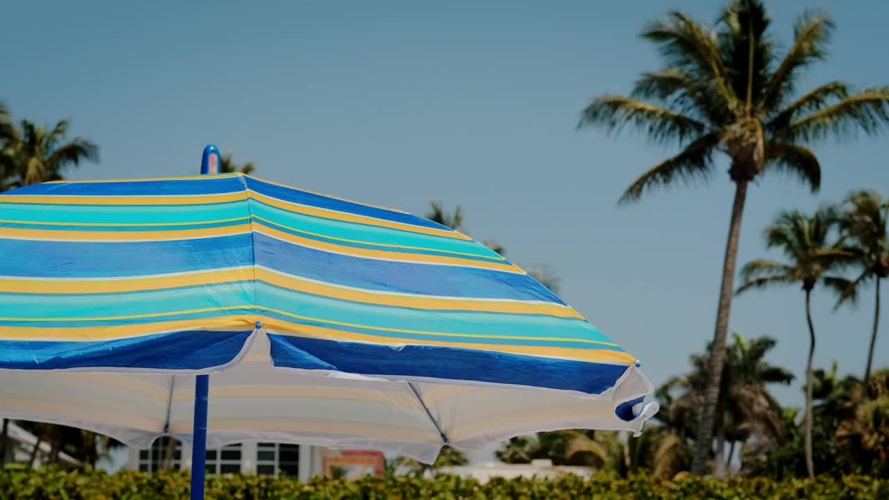 在一个阳光明媚的完美寒冷的日子里，沙滩上的条纹伞。遮住太阳，靠近点视频素材