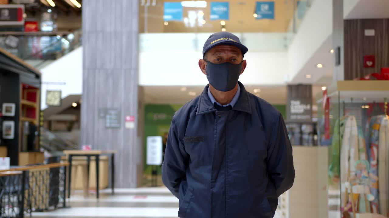 在大流行危机期间，商场的保安戴着防护口罩走过走廊视频素材
