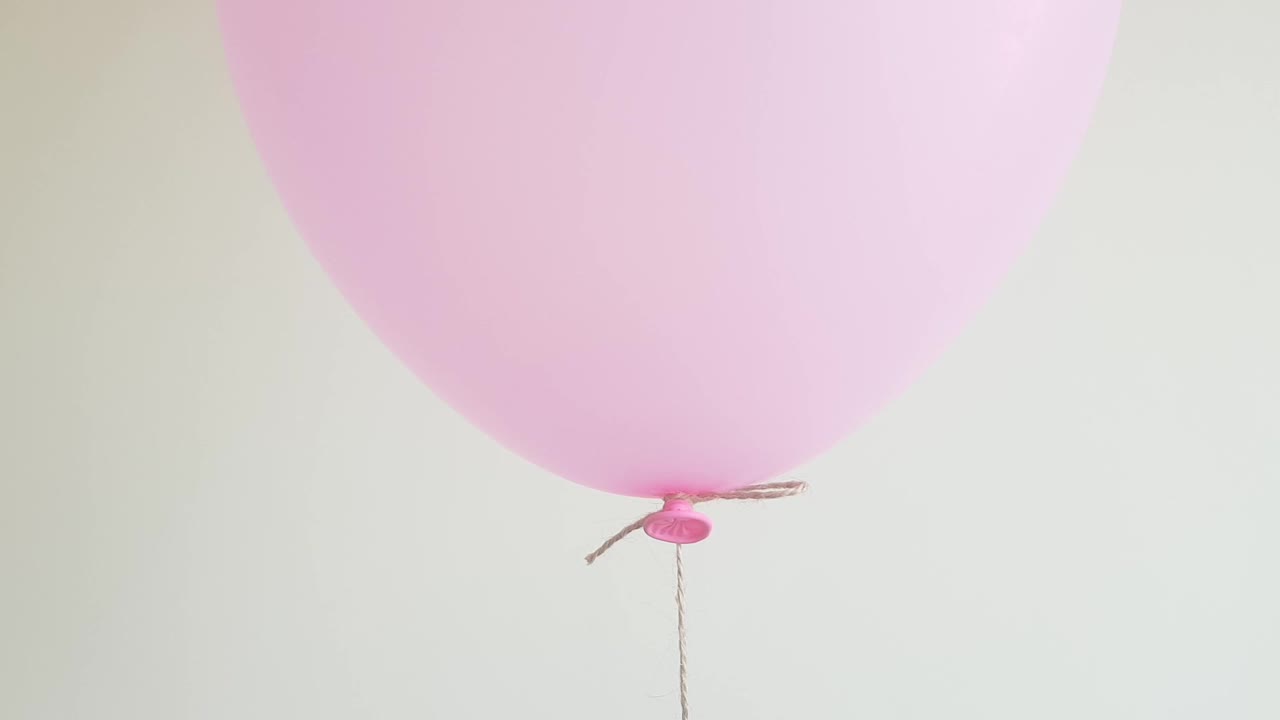 粉色的轻氦气球漂浮在白色的墙上，庆祝，生日的概念。特写镜头。视频下载