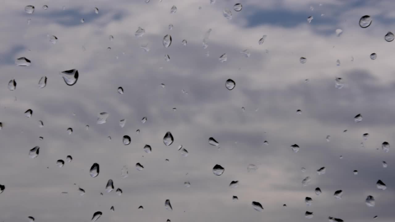 4K时间的雨滴在窗户上干燥，阴沉的，灰色的，滚动的云在背景。视频素材
