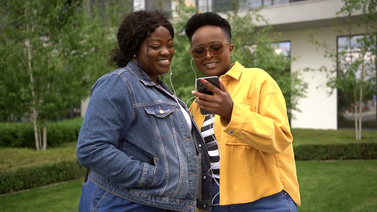 年轻的女性朋友们一起在城市里享受散步，用手机听音乐视频素材