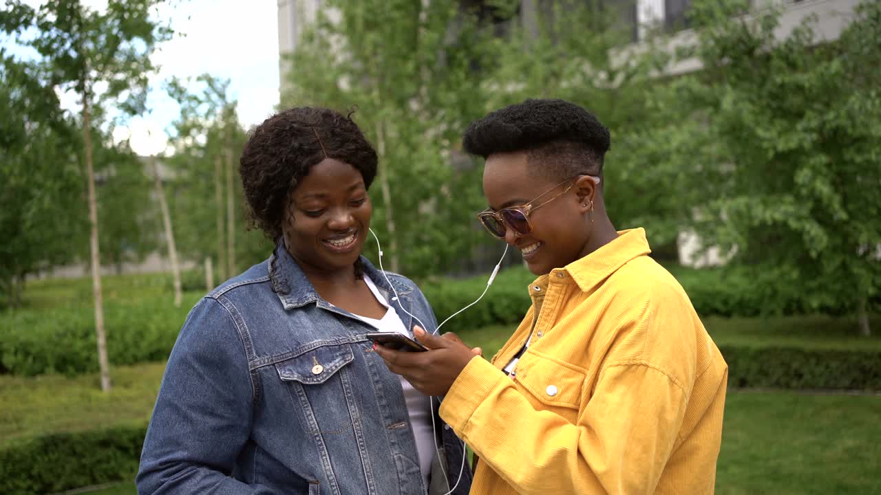 年轻的女性朋友们一起在城市里享受散步，用手机听音乐视频素材