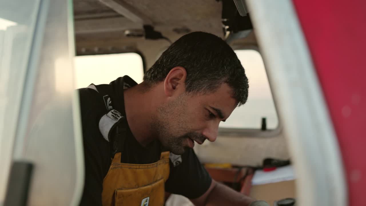 30歲出頭的白人漁民駕駛小型拖網漁船視頻下載