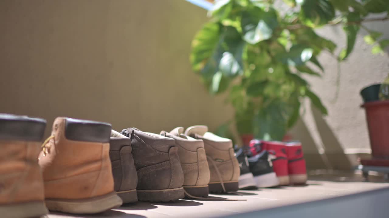 一排鞋在炎热的太阳下，在阳台旁边的室内植物视频下载