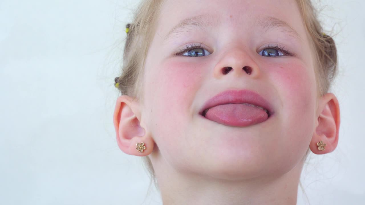一个小女孩露出了舌头和喉咙。张大嘴巴，伸出舌头的肖像。在视野清晰的情况下伸出长舌头。软腭和口腔给牙医。嘴张得大大的，舌头伸出来。视频素材